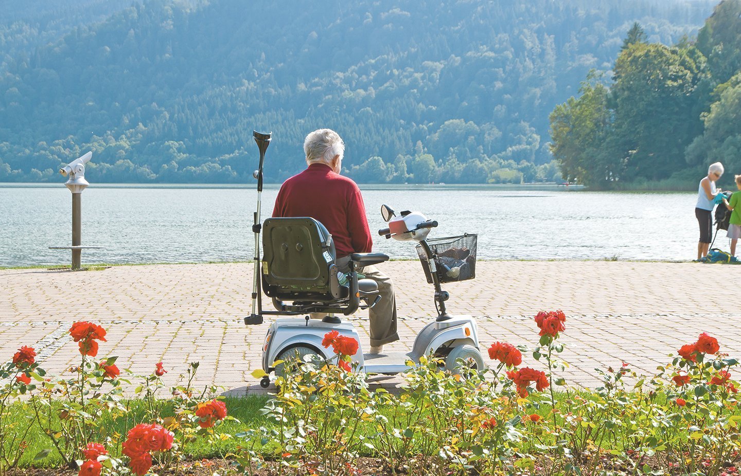 Älterer Mann sitzt auf Elektromobil und genießt den Ausblick aufs Wasser