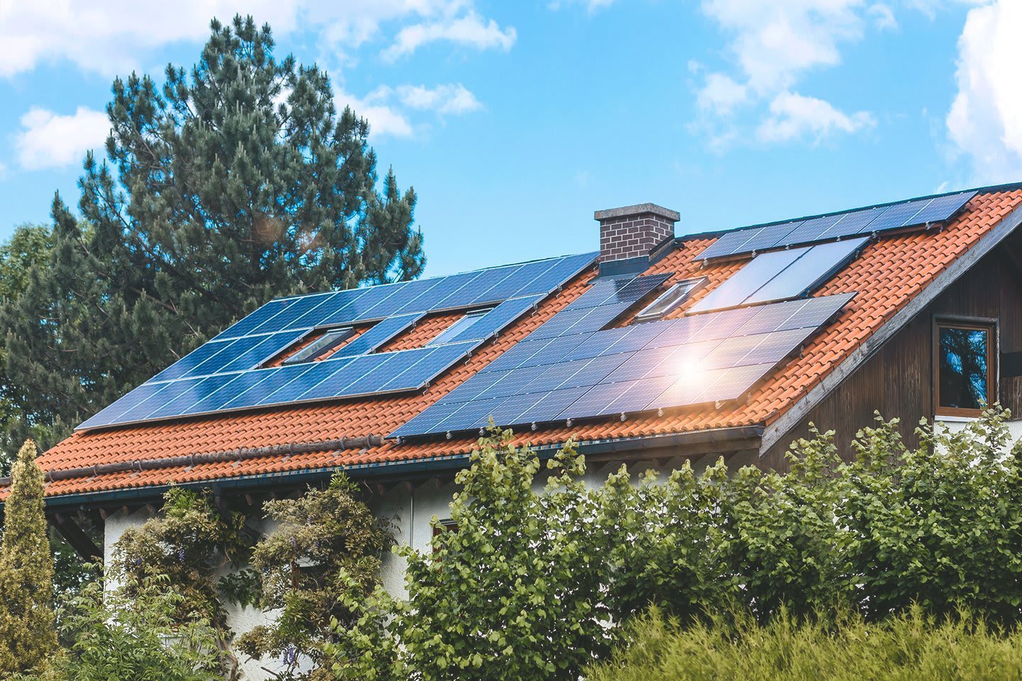 Einfamilienhaus im Grünen mit Photovoltaikanlage auf dem Dach bei sonnigem Wetter