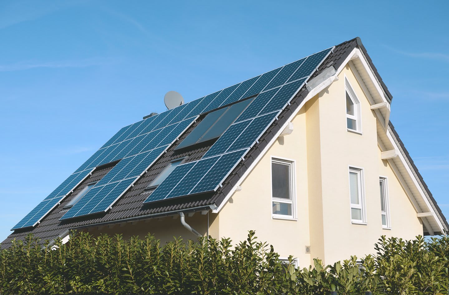 gepflegtes Einfamilienhaus mit großer Photovoltaikanlage vor blauem Himmel