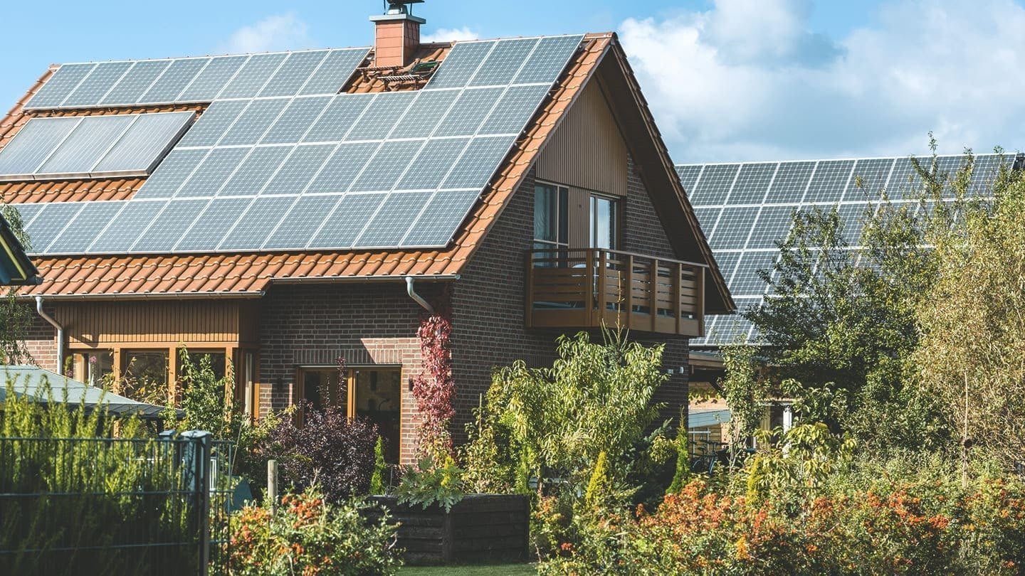 Zwei Wohnhäuser mit großer Solaranlage auf dem Dach in einem grünem Garten