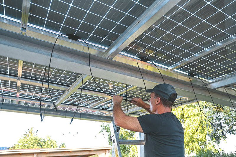Elektriker, der die Module eines Solar-Terrassendachs verbindet.