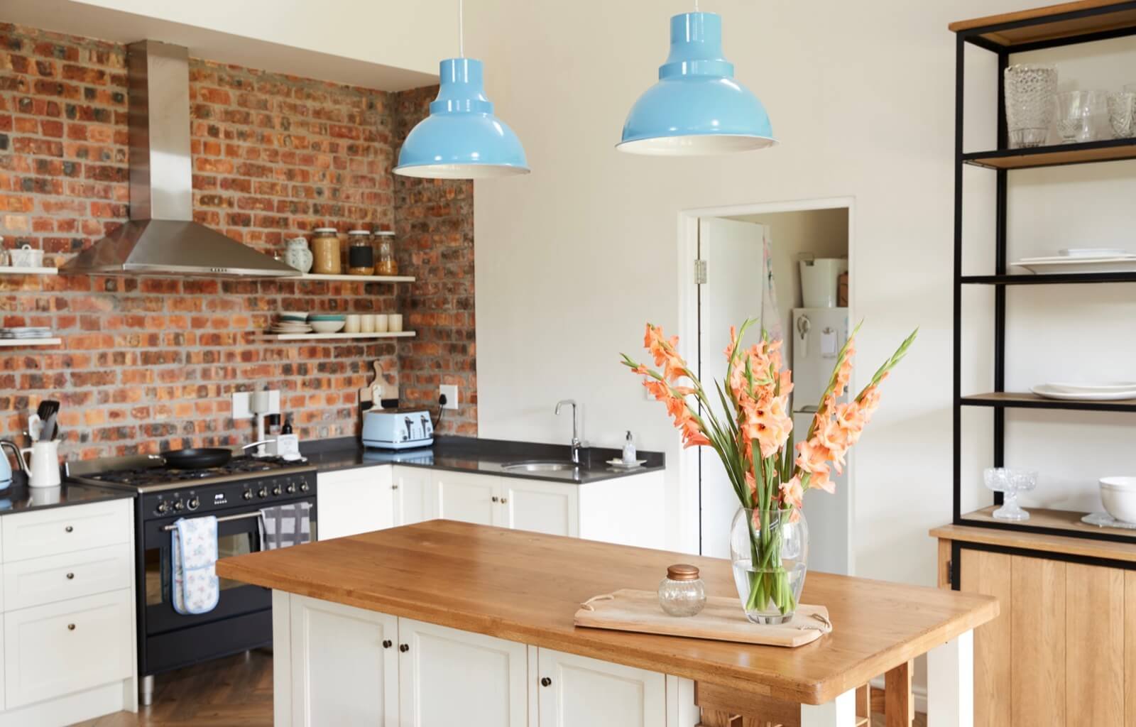 Landhausküche mit blauen Lampen und Holzarbeitsplatte