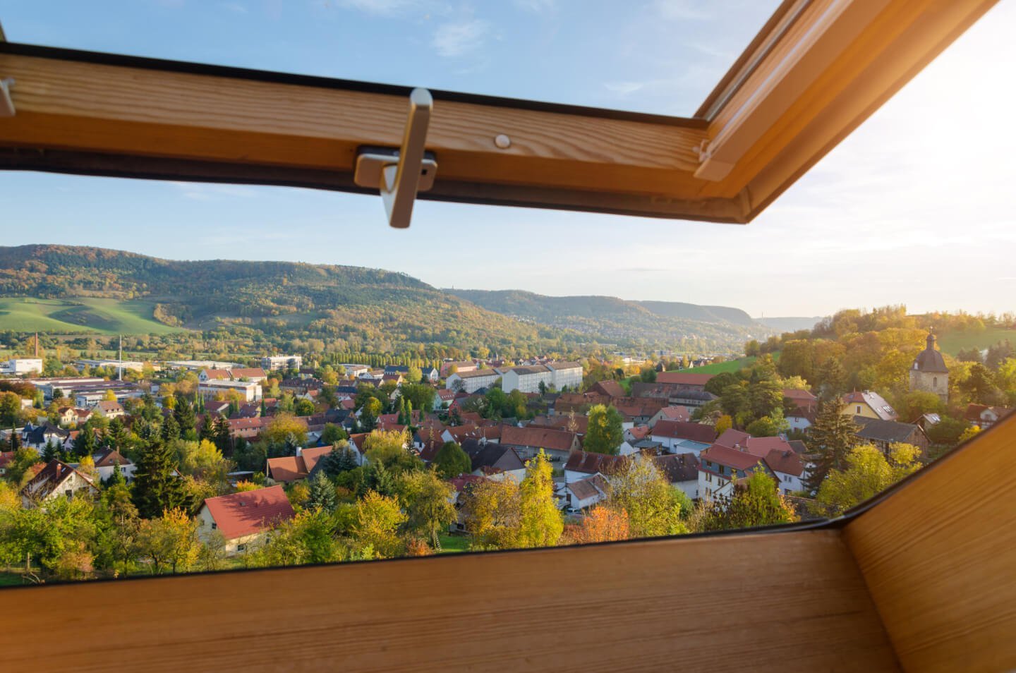 Dachfenster mit Holzrahmen mit Ausblick über die Stadt