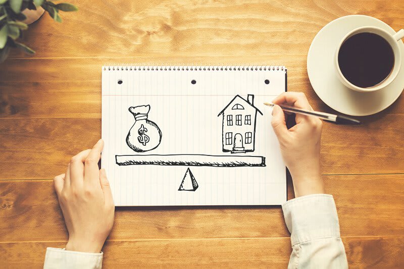 Frau zeichnet Waage zu Immobilienkosten auf ein Blatt Papier