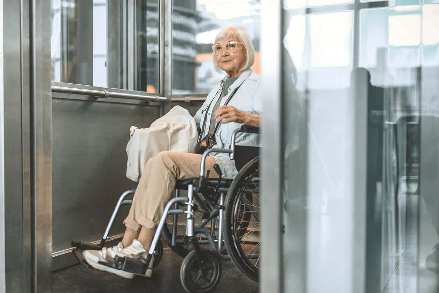 Ältere Frau im Rollstuhl im Fahrstuhl