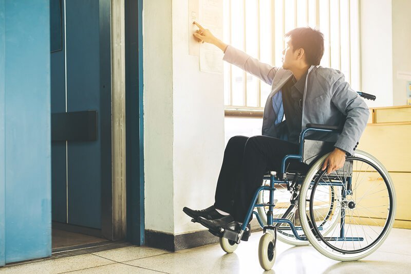 Mann im Rollstuhl vor Aufzug