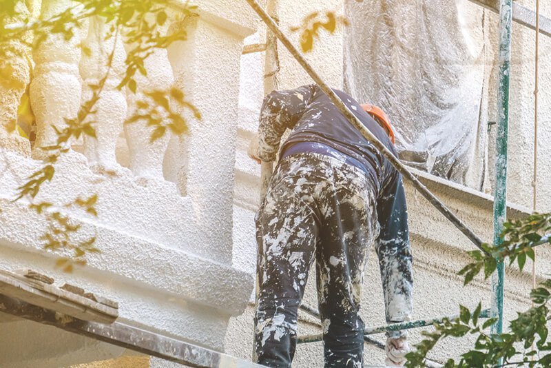Maler verputzt Fassade auf einem hohen Gerüst