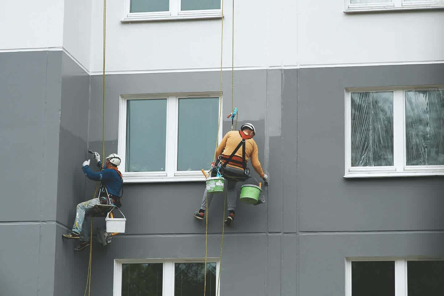 Zwei Maler streichen eine Fassade