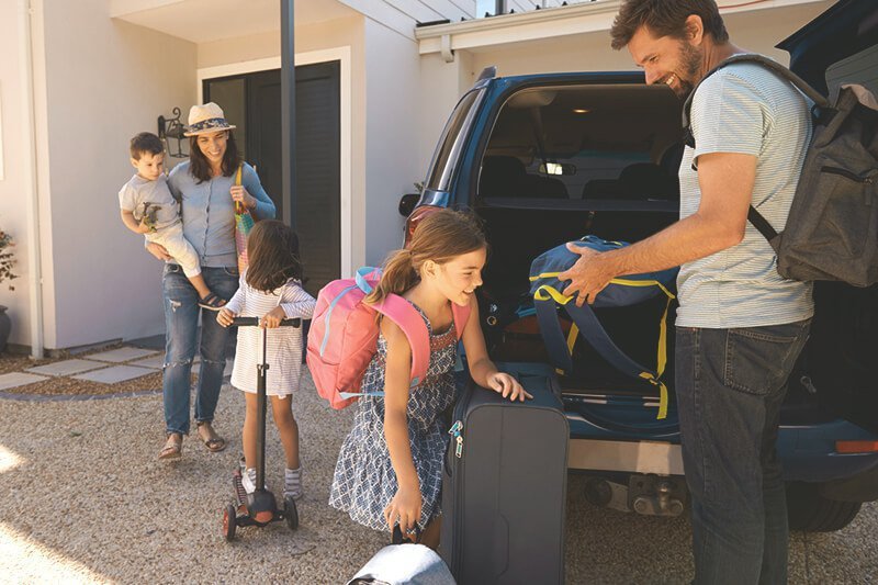 Familie packt Taschen in den Kofferraum eines Autos