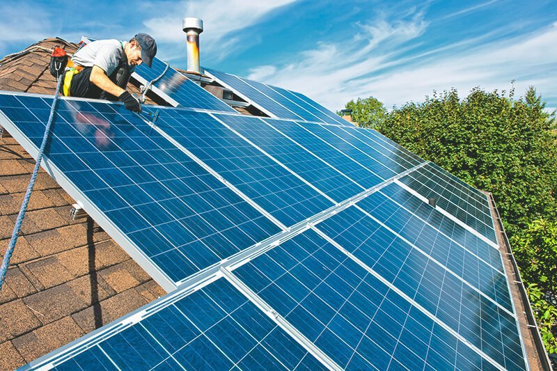 Handwerjer montiert Solaranlage auf Hausdach