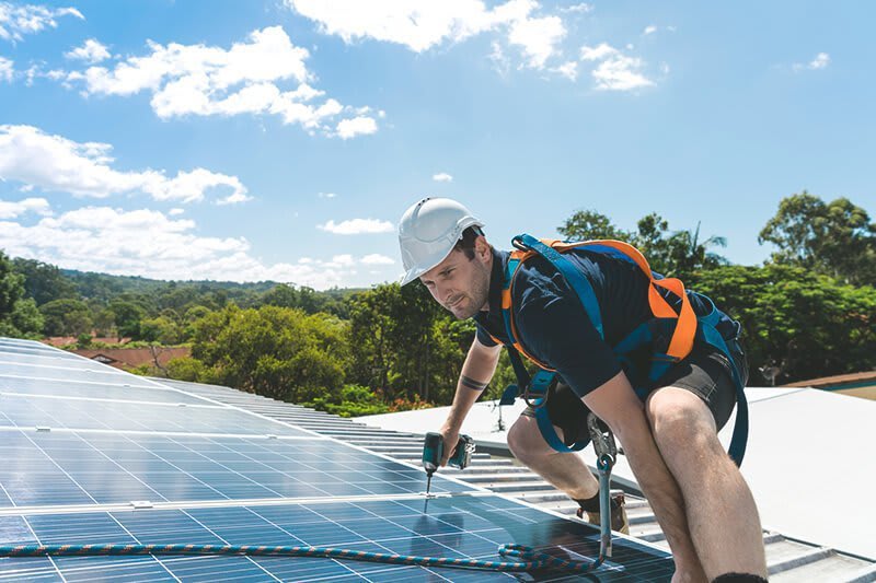 Handwerker montiert eine Solaranlage auf einem Hausdach