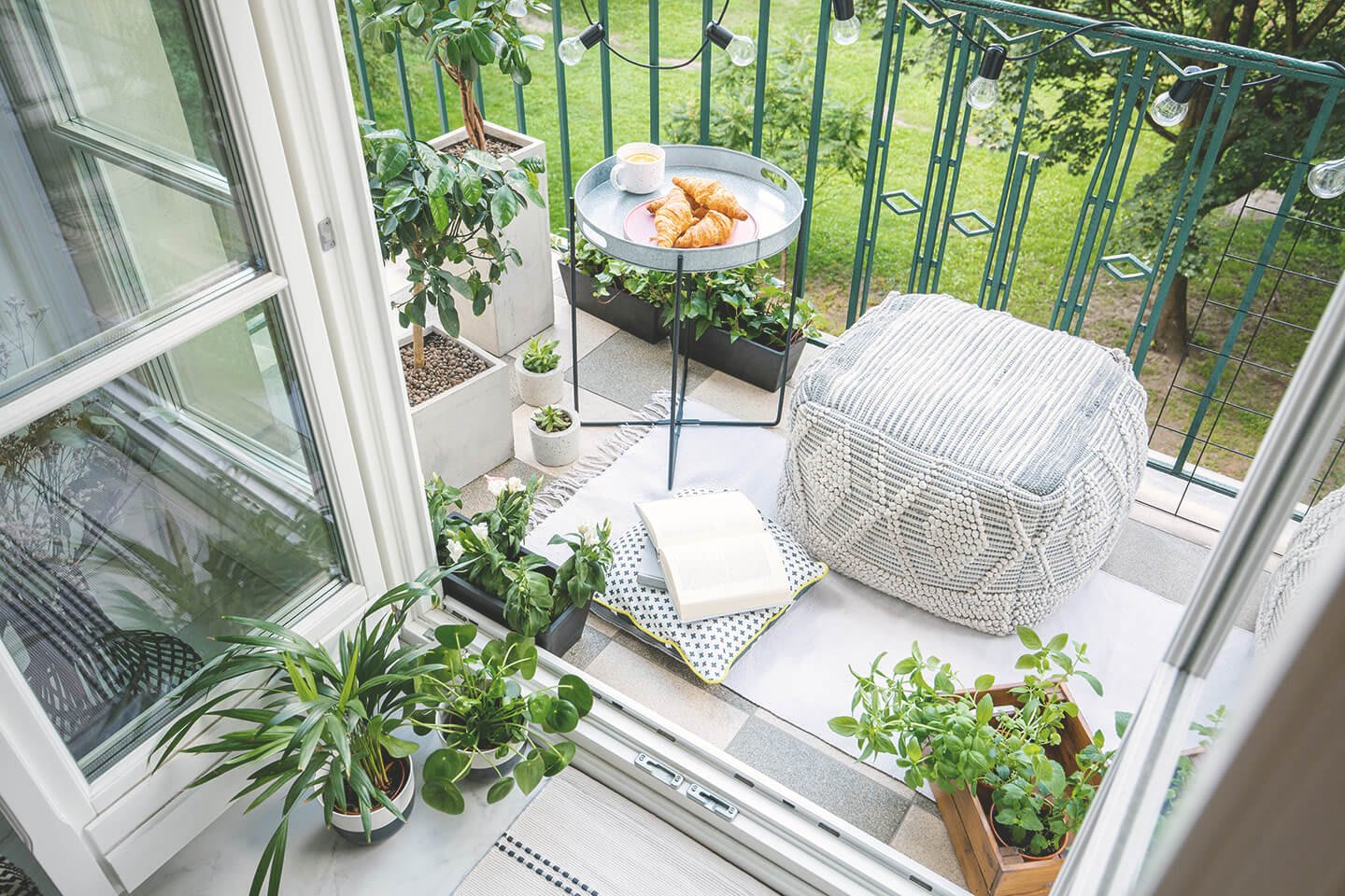 Kleiner Balkon mit Hocker, Pflanzen und einem Buch