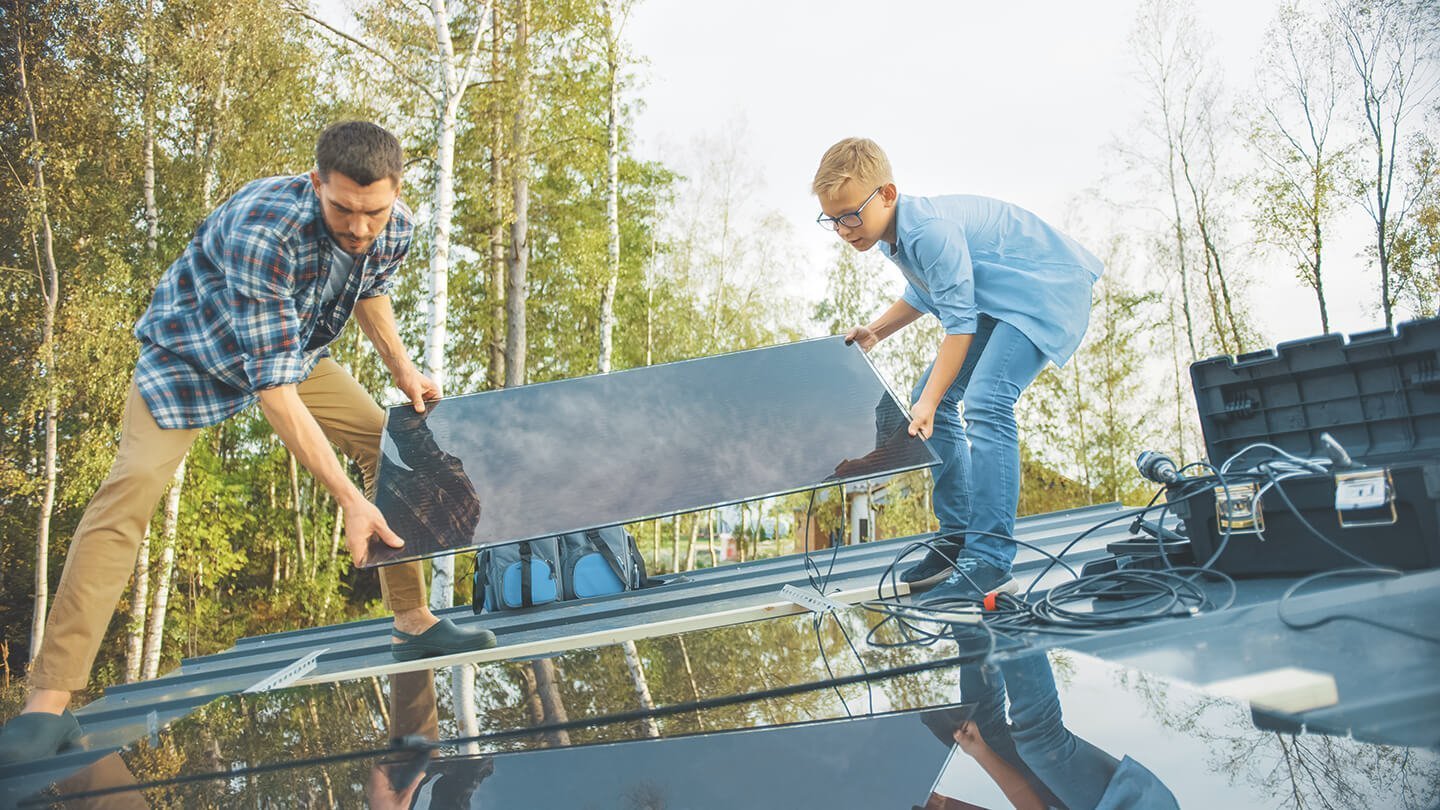 Sohn und Vater stehen auf Dach mit Solarmodul