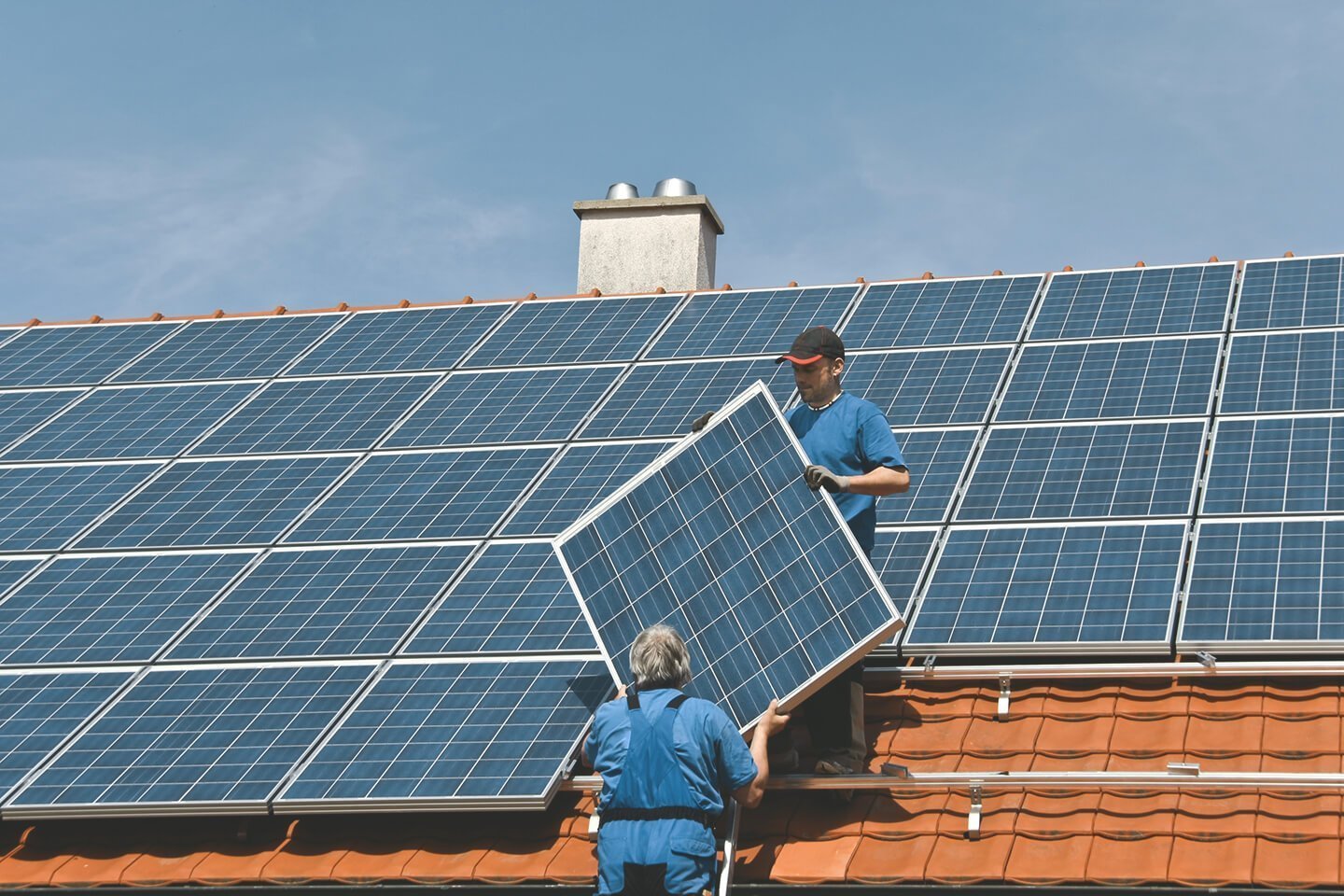 Handwerker decken Dach mit Solaranlage ein